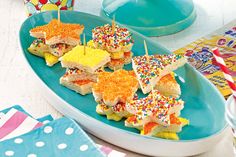 small sandwiches with colorful sprinkles are on a blue platter next to candy