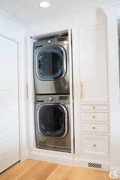 a washer and dryer in a room with white cabinets on either side of the door