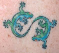 two lizards are depicted on the back of a woman's shoulder and neck tattoo