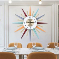 a clock mounted to the wall above a dining room table with chairs and place settings