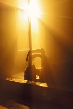 a person laying on the ground in front of a window with sunlight coming through it