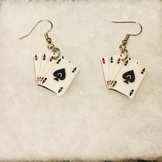 pair of earrings with playing cards on them sitting on top of a white cloth background