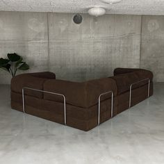 a brown couch sitting in the middle of a room next to a potted plant