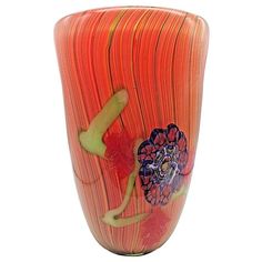 an orange vase with designs on the bottom and sides, sitting in front of a white background