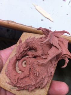 a person is holding a clay sculpture in their hand and it looks like a dragon