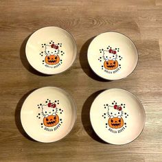 four white plates with designs on them sitting on a wooden table next to each other