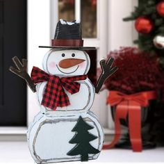 a snowman is standing in front of a door with his arms out and hat on