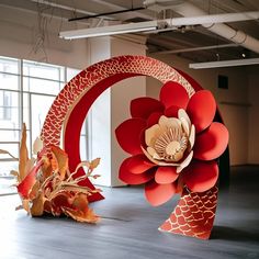 two large red paper flowers sitting on top of a wooden floor next to each other