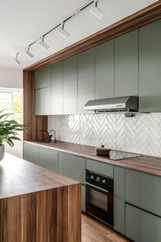 a modern kitchen with green cabinets and wood counter tops, along with a potted plant