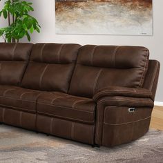 a brown reclining couch sitting on top of a carpeted floor next to a potted plant