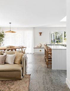 a living room filled with furniture next to a kitchen