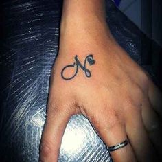 a person's hand with a tattoo on it and scissors in the middle of their fingers