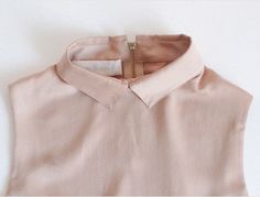 a pink shirt is hanging on the wall with a tag in it's collar