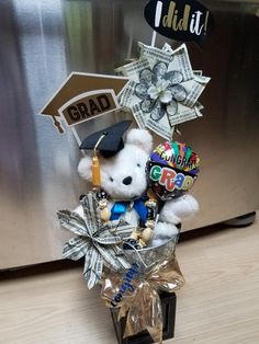 a white teddy bear wearing a graduation cap and holding balloons in front of a refrigerator