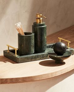 a wooden table topped with two green cups and soap dispenser next to each other