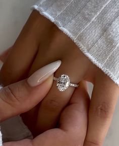 a woman's hand with a ring on it and a white manicured nail