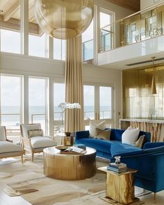 a living room filled with lots of furniture and large windows overlooking the ocean in front of it