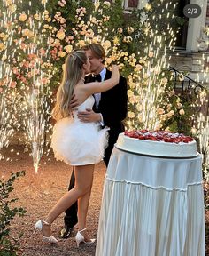 a man and woman kissing in front of a cake