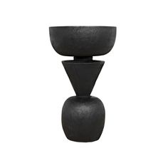 a black vase sitting on top of a white wall