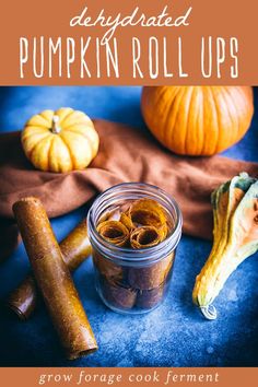 a glass jar filled with spices next to two pumpkins and an orange peel on a blue surface