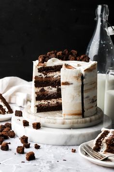 a cake sitting on top of a white plate next to a glass of milk and a bottle