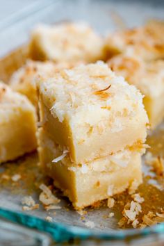 three pieces of cake sitting on top of a glass plate covered in coconut flakes