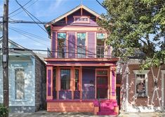 a pink and purple house sitting on the side of a road