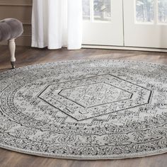 a large round rug with an intricate design on the floor in front of a window