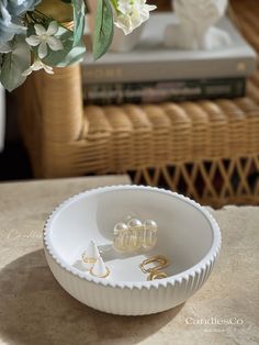 a white bowl sitting on top of a table next to a vase filled with flowers