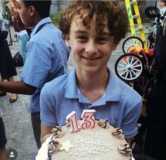 a young boy holding a birthday cake with frosting and icing on the top