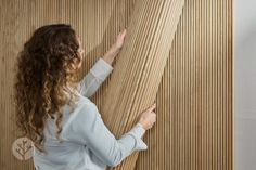 a woman is holding on to the side of a wooden wall with wood slats