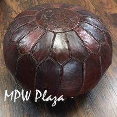 a brown leather poufce sitting on top of a wooden floor