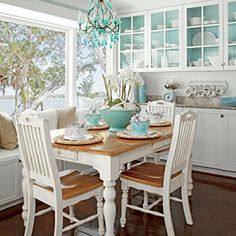 a dining room table and chairs in front of a window with the view of the ocean