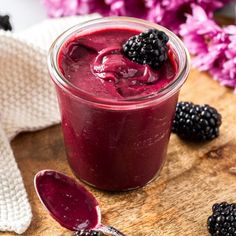 a glass jar filled with berries on top of a wooden cutting board next to some blackberries