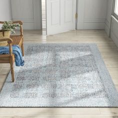 a room with a chair and rug on the floor in front of a door that has a potted plant next to it