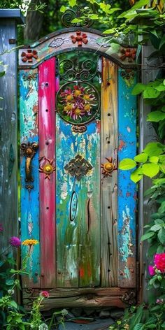 an old door is painted bright blue, pink and green with flowers around the edges