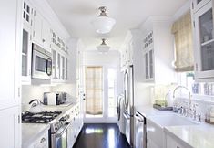 a large kitchen with white cabinets and an island in the middle is decorated with chandeliers