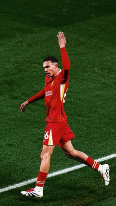 a soccer player is running on the field with his arms in the air as he celebrates