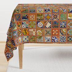 a table covered in colorful tiles on top of a white rug