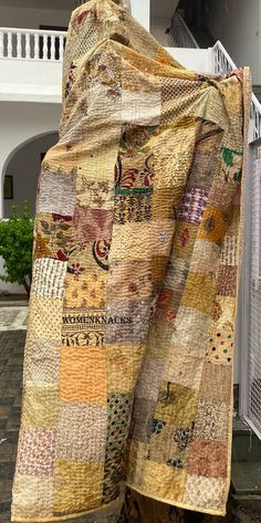 an old quilt is draped on the back of a chair in front of a house