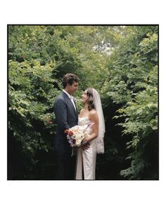 a bride and groom standing in front of trees