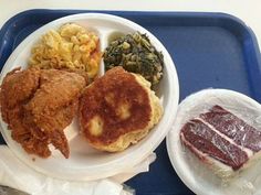 a tray with some food on it including meat, macaroni and cheese and other foods