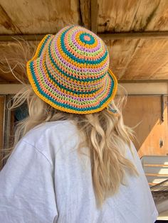 a woman wearing a multicolored crocheted hat looking at the back of her head