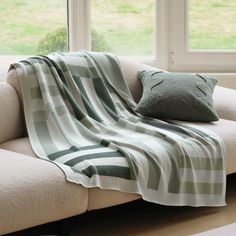 a couch with a blanket on it next to a window