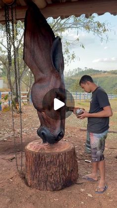 a man standing next to a statue of a horse on top of a tree stump