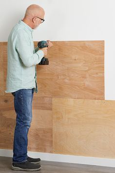 an older man is using a drill to install wood paneling on the side of a wall