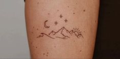 a woman's arm with a tattoo on it that has mountains and stars in the sky