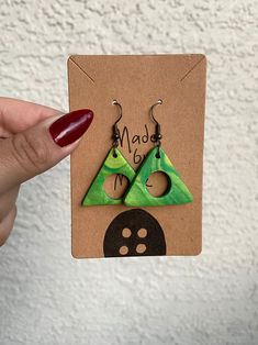 a pair of green triangle shaped earrings sitting on top of a card