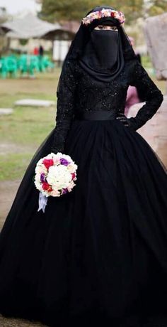 a woman in a black dress with flowers on her head and wearing a hijab