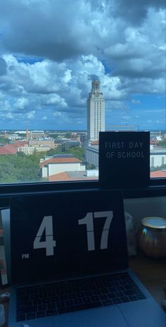 an open laptop computer sitting on top of a desk next to a window with a view of the city